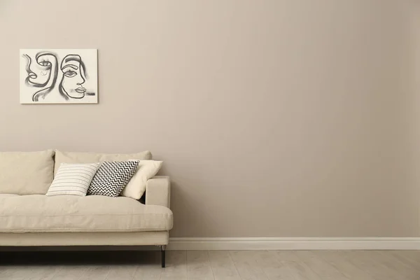 Modern comfortable sofa and picture near wall in room. Interior design