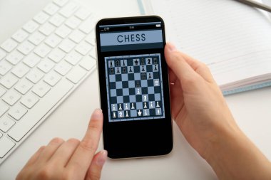 Sofrada akıllı telefonda online satranç oynayan kadın, yakın plan.