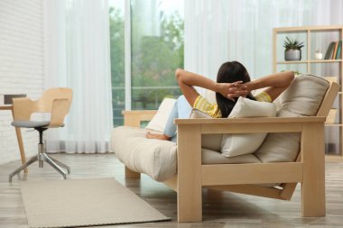 Evdeki kanepede dinlenen genç bir kadın. Metin için boşluk