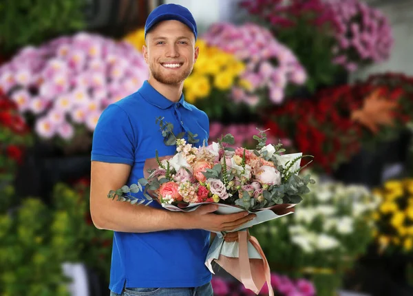 花の店で美しい花束を持つ配達人 — ストック写真