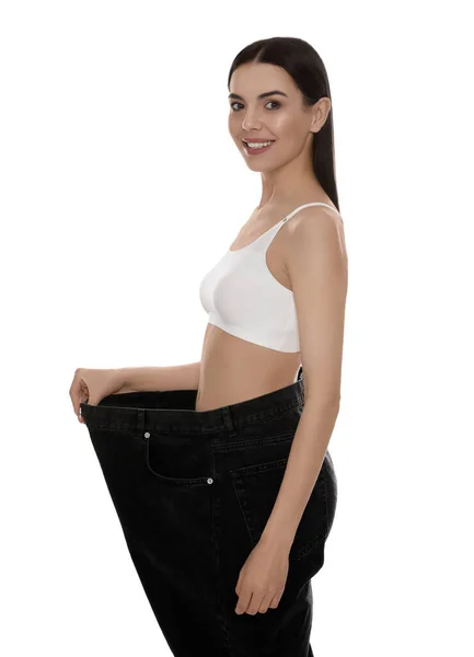 白い背景に体重減少後の大きなジーンズを身に着けている若い女性 — ストック写真