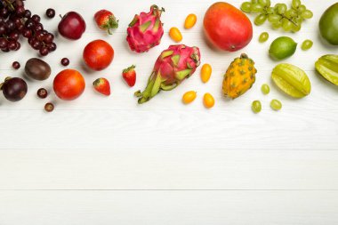 Beyaz ahşap masa üzerinde bir sürü lezzetli egzotik meyve, düz bir şekilde yatıyordu. Metin için boşluk