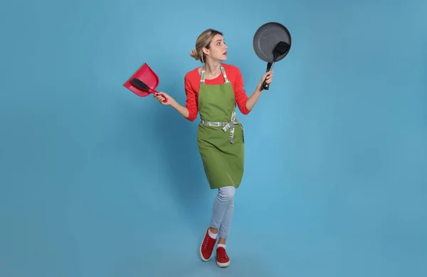 Jonge Huisvrouw Met Stofblik Borstel Koekenpan Spatel Lichtblauwe Achtergrond — Stockfoto