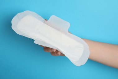 Açık mavi arka planda hijyenik peçete tutan kadın, yakın plan.
