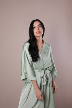 Bej arka planda açık ipek bornozlu güzel bir bayan.