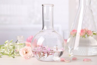 Beyaz ahşap masada Rosebay çiçekleriyle dolu bir şişe. Gerekli yağ çıkarma