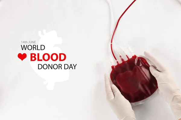 World Donor Day. Doctor in gloves holding blood pack on white background, top view