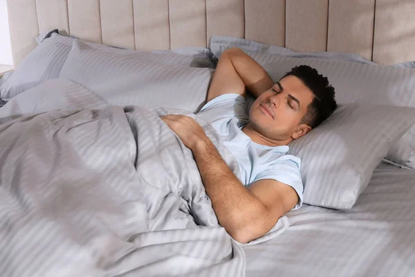 Açık Gri Çizgili Çarşaflarla Rahat Bir Yatakta Uyuyan Bir Adam — Stok fotoğraf