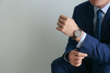 Gri arka planda lüks kol saati olan bir iş adamı, yakın plan. Metin için boşluk