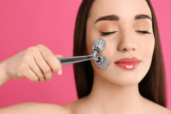 Mujer Usando Rodillo Metal Sobre Fondo Rosa Primer Plano —  Fotos de Stock