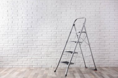 Beyaz tuğlalı duvarın yanındaki modern metal merdiven. Metin için boşluk