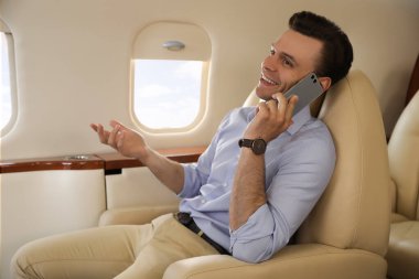 İş adamı uçuş sırasında cep telefonuyla konuşuyor.