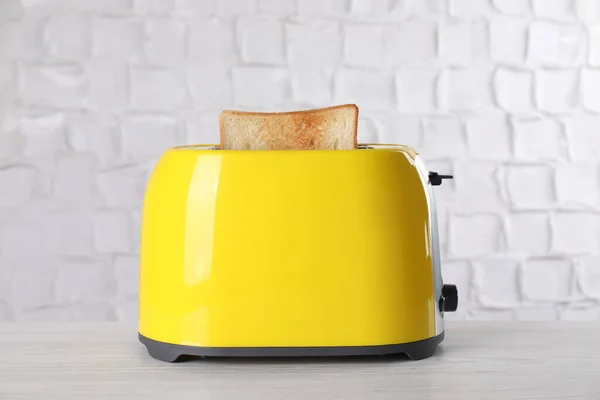 现代烤面包机 白色木制桌子上有一片面包 — 图库照片