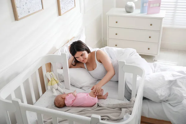 Feliz Madre Joven Descansando Cerca Cuna Con Bebé Recién Nacido — Foto de Stock