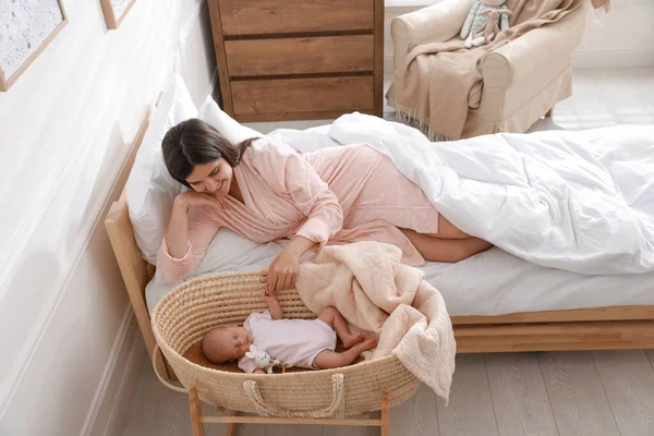 Feliz Joven Madre Descansando Cerca Cuna Con Bebé Recién Nacido — Foto de Stock