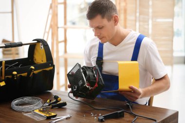 Profesyonel teknisyen içeride elektrikli vantilatör ısıtıcısını tamir ediyor.