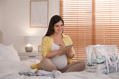 Hamile kadın evdeki doğum hastanesi için paket listesi yazıyor.