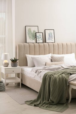 Beyaz duvarın yanında şık gri çarşaflı bir yatak.