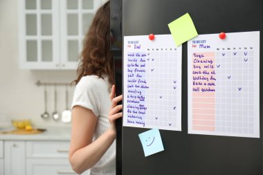Mutfak kapısında liste yapan buzdolabının yanındaki kadın.