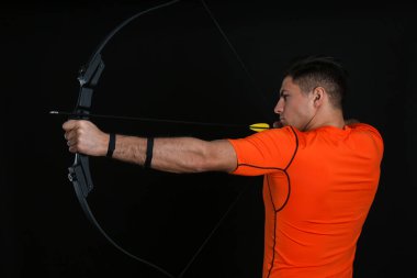 Ok ve yaylı adam siyah arka planda okçuluk çalışıyor.