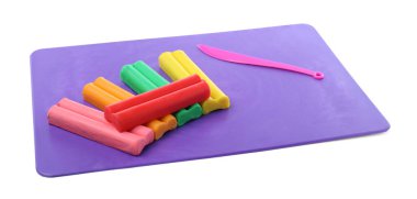 Beyaz arka planda birçok farklı renkli plastik parçalar ve heykel bıçağı var.