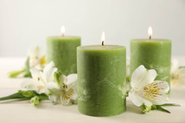 Beyaz ahşap masada yanan mumlar ve güzel çiçekler.