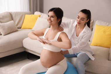 Doula oturma odasında hamile bir kadınla çalışıyor. Çocuk doğumu hazırlığı