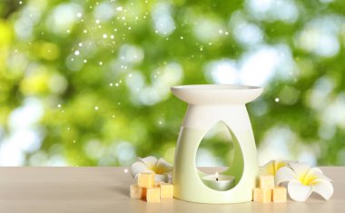 Zarif aroma lambası. Ağda küpleri ve açık masa üzerinde çiçekler. Yazı için yer var. Bokeh etkisi
