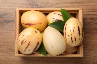 Tahta masada yeşil yapraklı taze pepino kavunları.