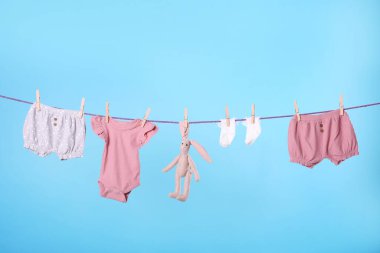 Temiz çocuk giysileri turkuaz arka planda çamaşır ipine asılı.
