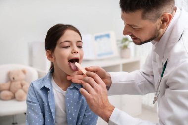 Çocuk doktoru hastanede küçük bir kızı muayene ediyor.