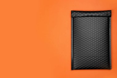 Turuncu arka planda baloncuk ambalajlı bir zarf, üst manzara. Metin için boşluk