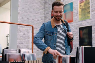 Delikanlı mağazada plak seçiyor.