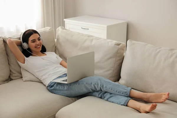 Frau Mit Laptop Und Kopfhörer Liegt Hause Auf Sofa — Stockfoto