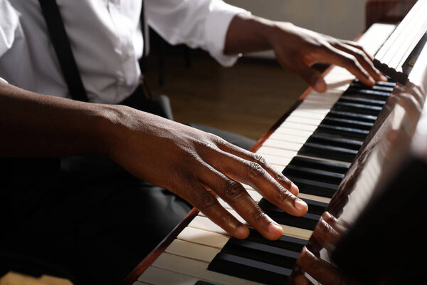 Афроамериканец играет на пианино в помещении, крупным планом. Талантливый музыкант