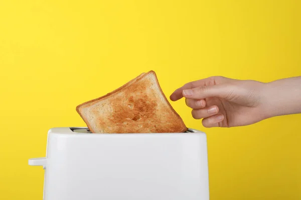Vrouw Neemt Sneetje Brood Uit Witte Broodrooster Gele Achtergrond Closeup — Stockfoto