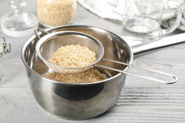 Gri ahşap masada pirinçli elek