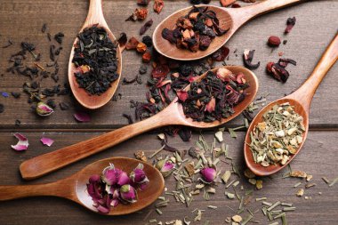 Tahta masada farklı çay ve kaşıklarla düz kompozisyon.