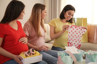 Mutlu hamile kadınlar alışveriş yaptıktan sonra birlikte oturma odasında vakit geçiriyorlar.