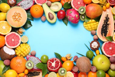 Açık mavi arka planda farklı egzotik meyvelerin çerçevesi düz. Metin için boşluk