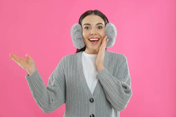 美しいです若いです女性身に着けていますEarmuff上のピンクの背景 — ストック写真