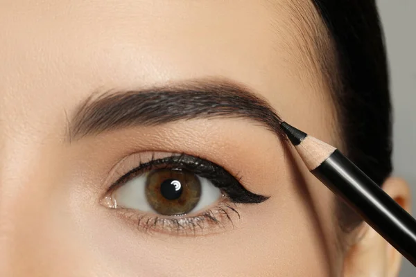 若い女性は 鉛筆で眉の形状を修正します クローズアップビュー — ストック写真