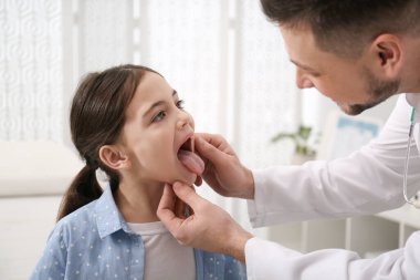 Çocuk doktoru hastanede küçük bir kızı muayene ediyor.