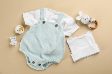 Bebek kıyafetleri ve aksesuar bej arka planlı düz kompozisyon