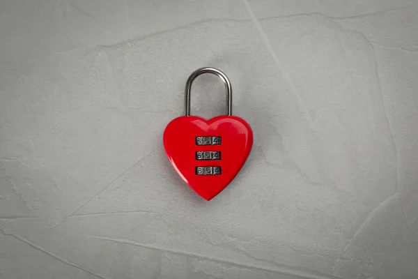 Red heart shaped combination lock on light grey table, top view