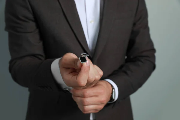 Elegante Uomo Che Tiene Gemelli Contro Sfondo Grigio Primo Piano — Foto Stock