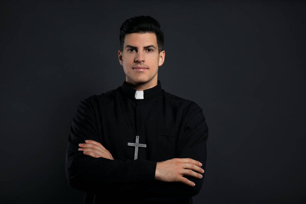 Priest in cassock with cross on black background