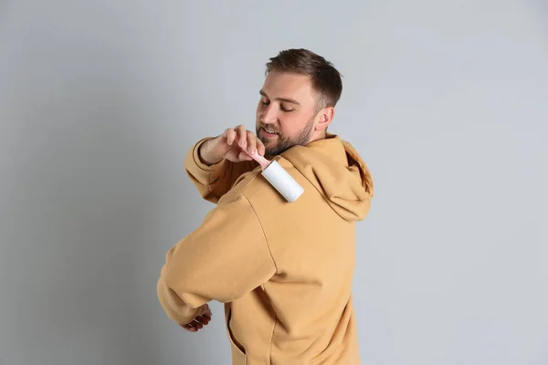 Jongeman Schoonmaken Van Kleding Met Pluisrol Grijze Achtergrond — Stockfoto