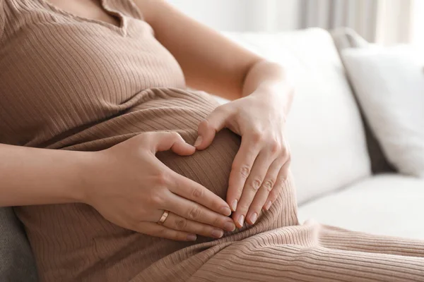 Zwangere Jonge Vrouw Maakt Hart Met Haar Handen Buik Thuis — Stockfoto