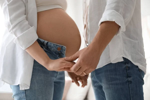 妊娠中の若い女性と大きな腹と彼女の夫は家で手を携えて クローズアップ — ストック写真